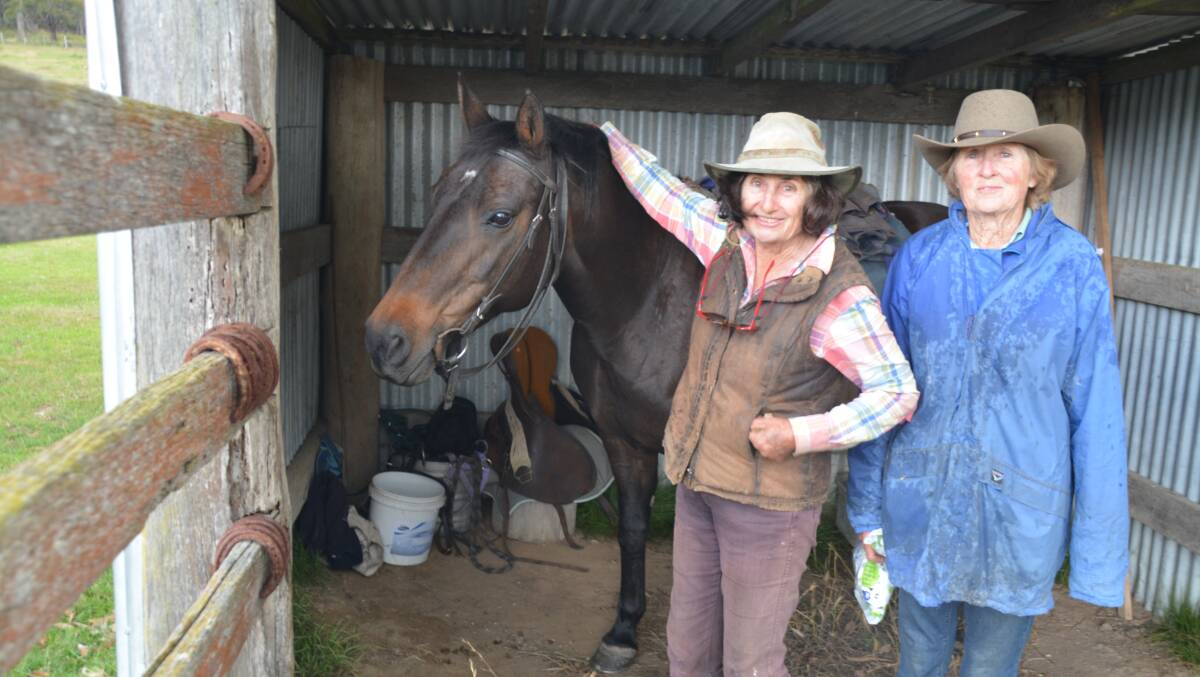 Rain, hail or shine: Wainie Robertson and Wisty Halloran with Wainie's horse - taking shelter from a storm that blew in while they were drenching cattle. Photo: Stephanie van Eyk