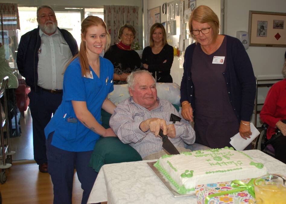 Erin McGuffog and Walcha Multipurpose Service Manager Kris Smith help long term Elizabeth Crosse wing resident Keith Stiers cut the anniversary cake