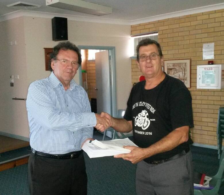 John Alexander from the RMS Grafton office receives a petition containing 10,700 signatures of people who are against lowering the speed limit on the Oxley Highway from Ken Healey on Monday.