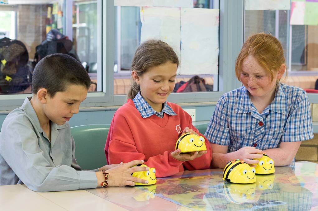 BEE SURE TO LEARN: Ethan Naylor, Charlotte Overton and Sarah Morris use Bee Bots, which are a type of floor robot, to introduce them to the language of programming. 