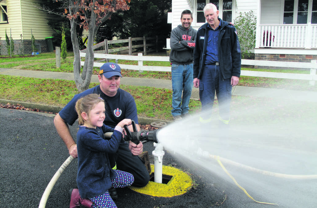 David Dunn helps Mollie Furneaux hold the hose while dad Jiah Furneaux and captain Peter Dunn look on.