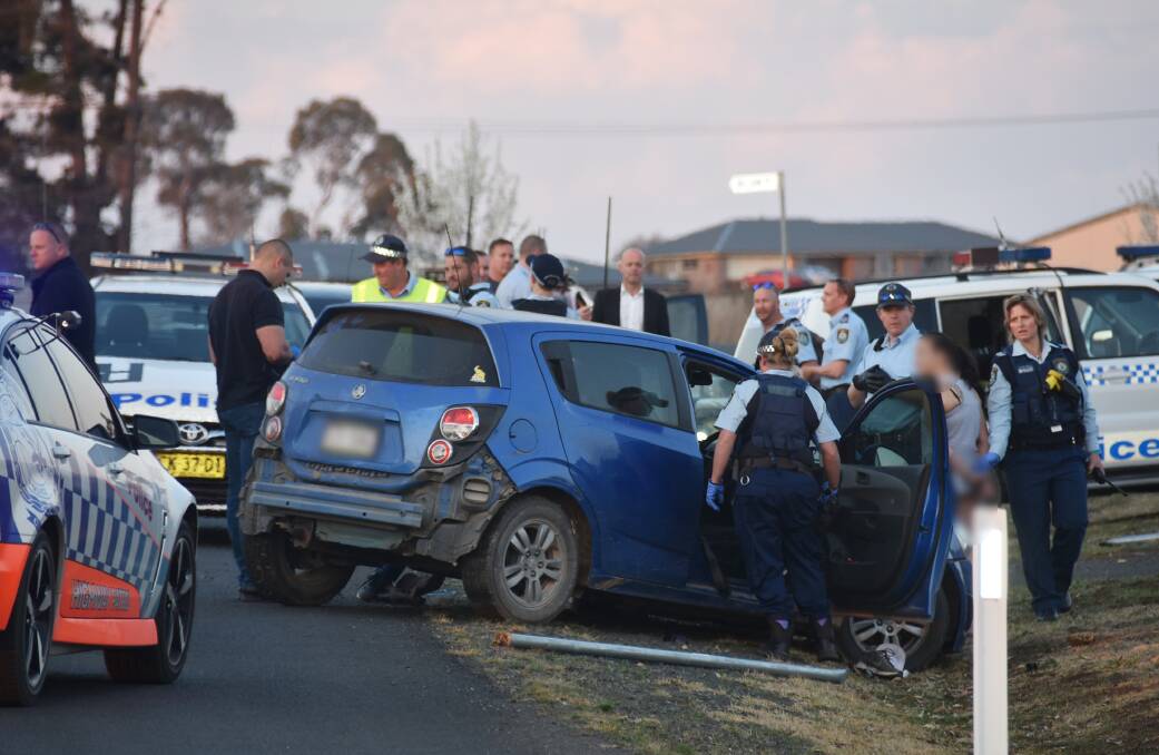 Under arrest: Police at the scene where a man and woman were pulled from the Holden  after it crashed on Post Way outside of Armidale on Wednesday. Photo: Laurie Bullock