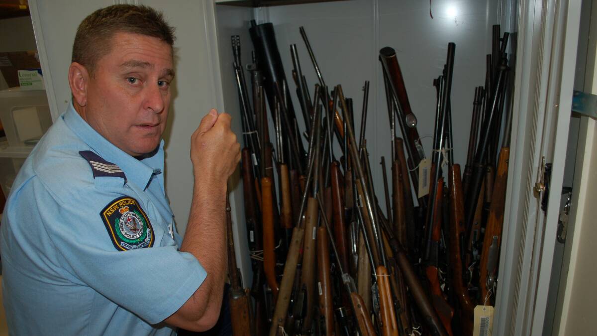 Sergeant Anthony Smith with some of the firearms handed in to police at Walcha Police Station