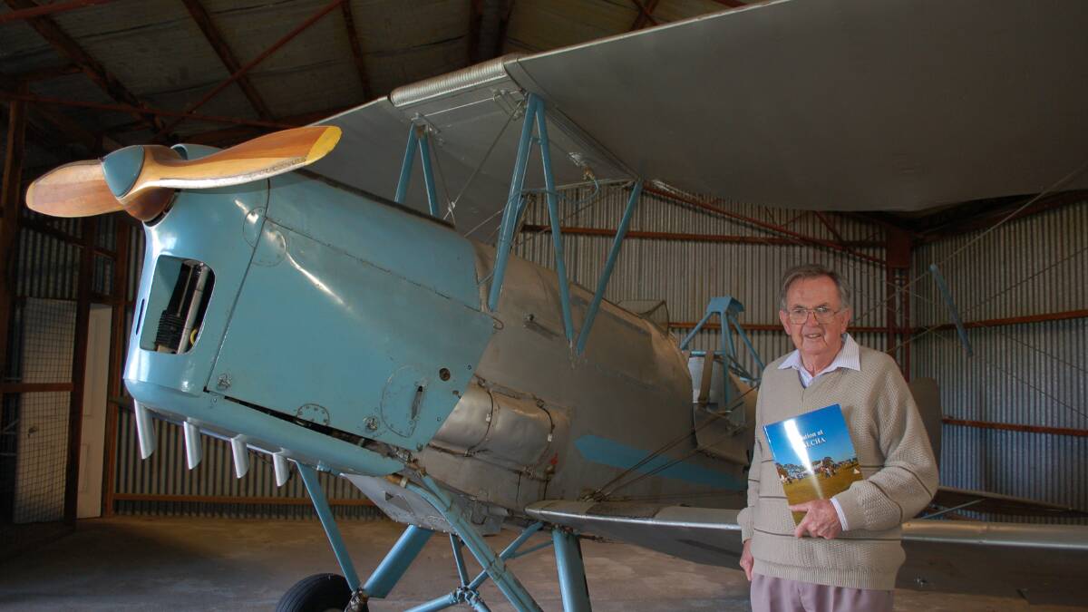 Cleared for take off: Bob Walsh holds his new book 'Aviation at Walcha' next to the Tiger Moth VH-PCB (formerly registered as VH-ASQ) in the Walcha Pioneer Cottage hangar