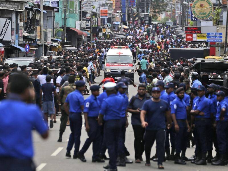 Sri Lankan police clear the road as an ambulance drives through carrying the injured in Colombo.