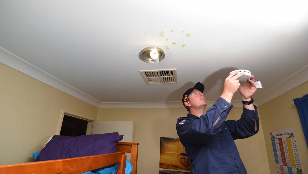 SAFETY CHECKS: Tamworth fire fighter Phil Moore installs a new smoke alarm. Photo:Gareth Gardner 110816GGC01